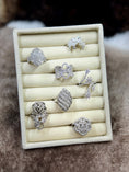 Load image into Gallery viewer, Set of silver rings displayed on a white ring holder against a brown background