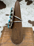 Load image into Gallery viewer, Side view turquoise flower ring on wood stand with cowhide background
