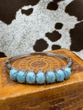 Load image into Gallery viewer, Silver Hinged Bangle Bracelet with Larimar Cabochons on leather jewelry box with cowhide background