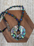 Load image into Gallery viewer, Beaded Colorful Necklace with Inlayed Multi Colored Squares Circle Pendant on brown wood block and white background