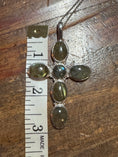 Load image into Gallery viewer, Silver pendant with green stones on a wooden surface with a ruler for scale.