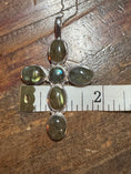 Load image into Gallery viewer, Silver pendant with green gemstones on a wooden surface with a ruler for scale.