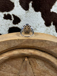 Load image into Gallery viewer, Underside of ring sitting on a wood block with cowhide background