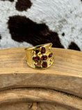Load image into Gallery viewer, side view Vintage Gold Plated Cross Ring with Garnets on wood block with cowhide background