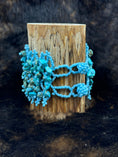Load image into Gallery viewer, backside of Handcrafted Turqoise Beaded Bracelet around a wood cup with dark fur background