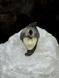 Load image into Gallery viewer, Bali Carved Bone Face Goddess Ring with Amethyst Colored Stone on white rock with black background