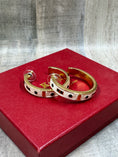 Load image into Gallery viewer, QVC Kenneth Jay Lane Enamel Statement Hoop Earrings laying on red original box with wood background