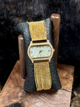 Load image into Gallery viewer, Peugeut Gold and Crystal Ladies Watch on black leather and wood stand with fur background