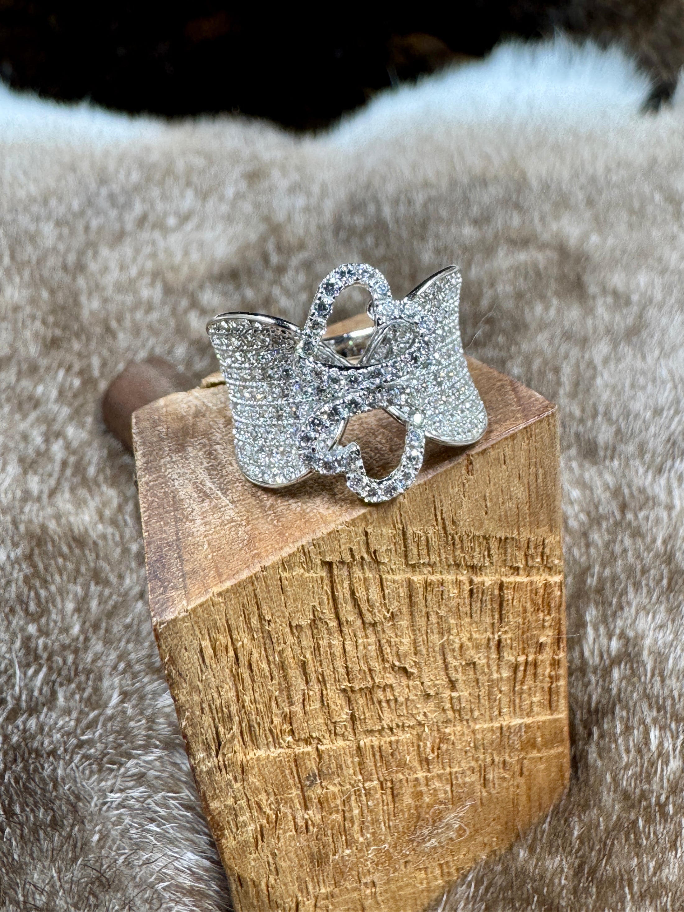 Silver hearts ring on a wooden block with a fur background