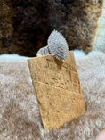 Load image into Gallery viewer, Silver ring with a textured design on a wooden stand against a fur background
