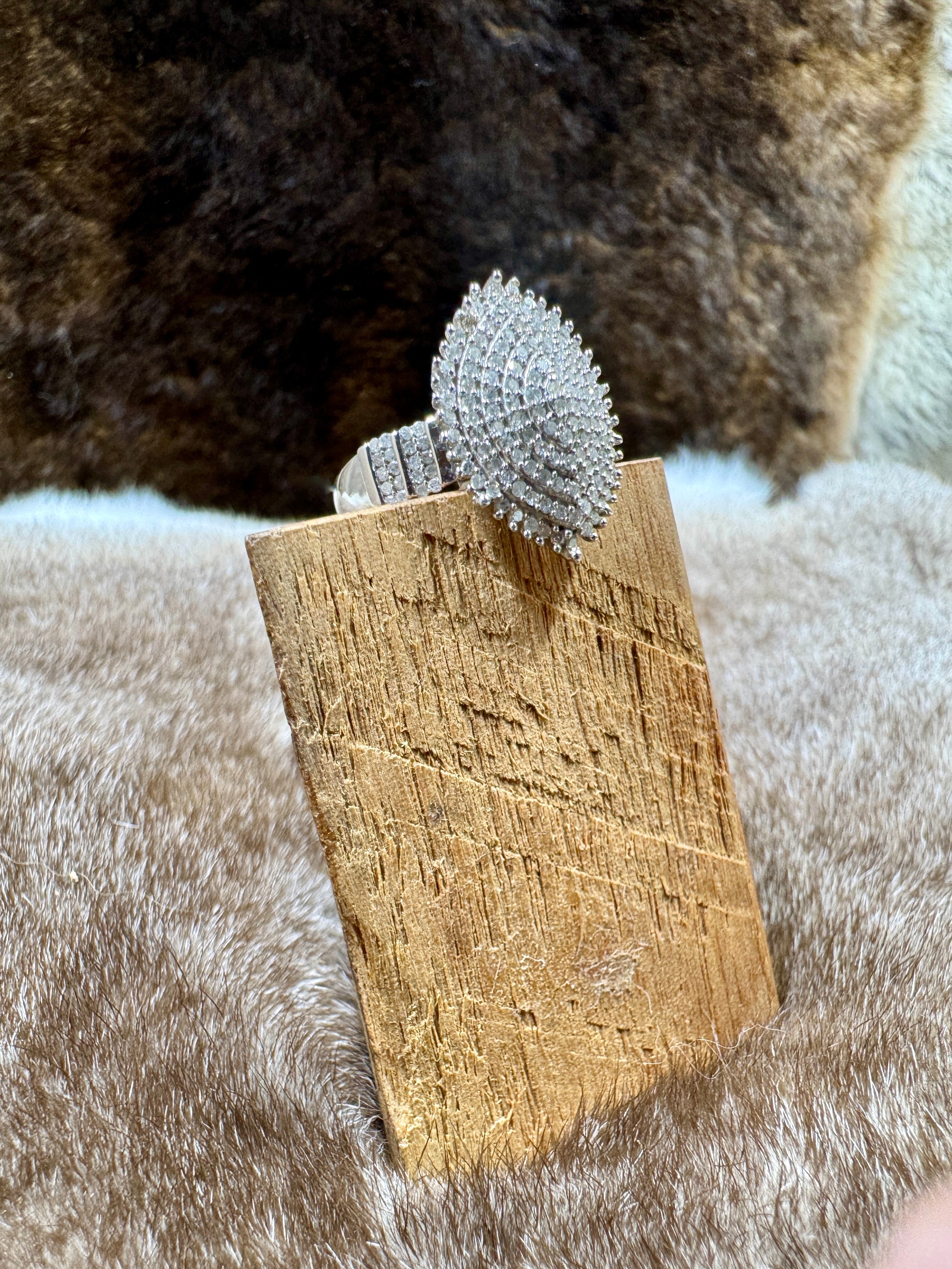 Silver ring with a textured design on a wooden stand against a fur background