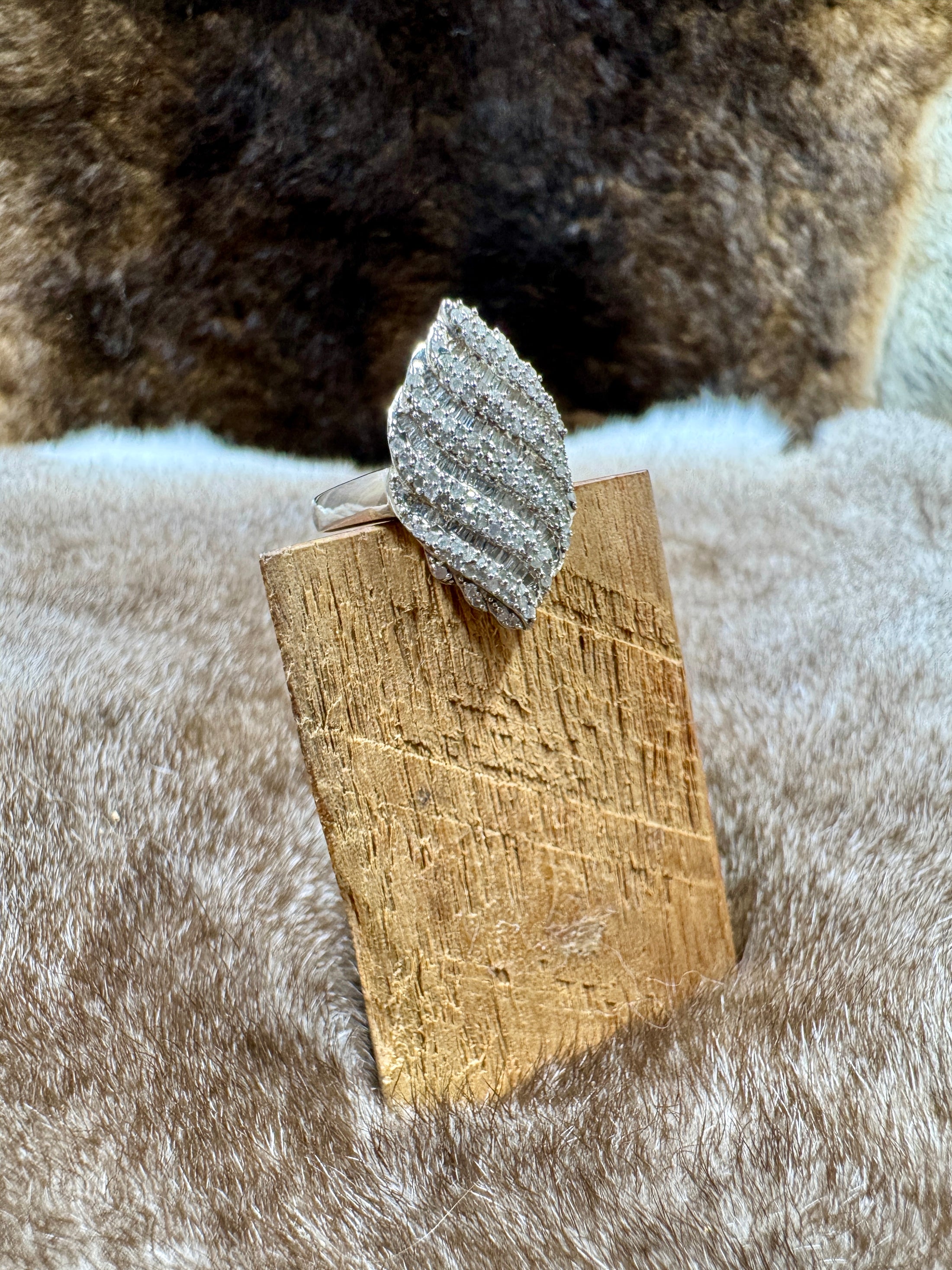 Silver leaf-shaped ring on a wooden stand with a fur background