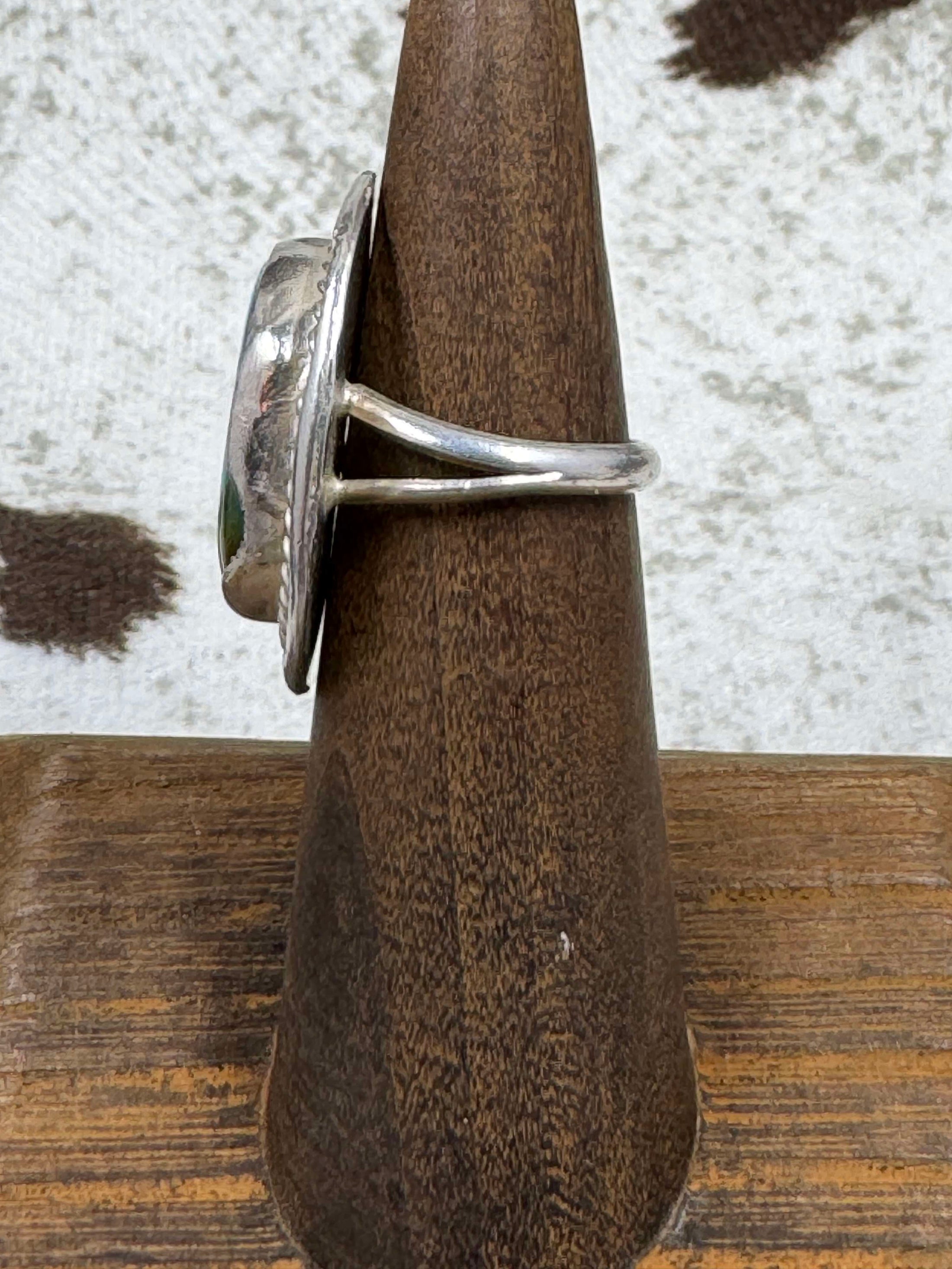 Side view of Vintage Sterling Silver and Turquoise Ring on wood stand with cowhide background