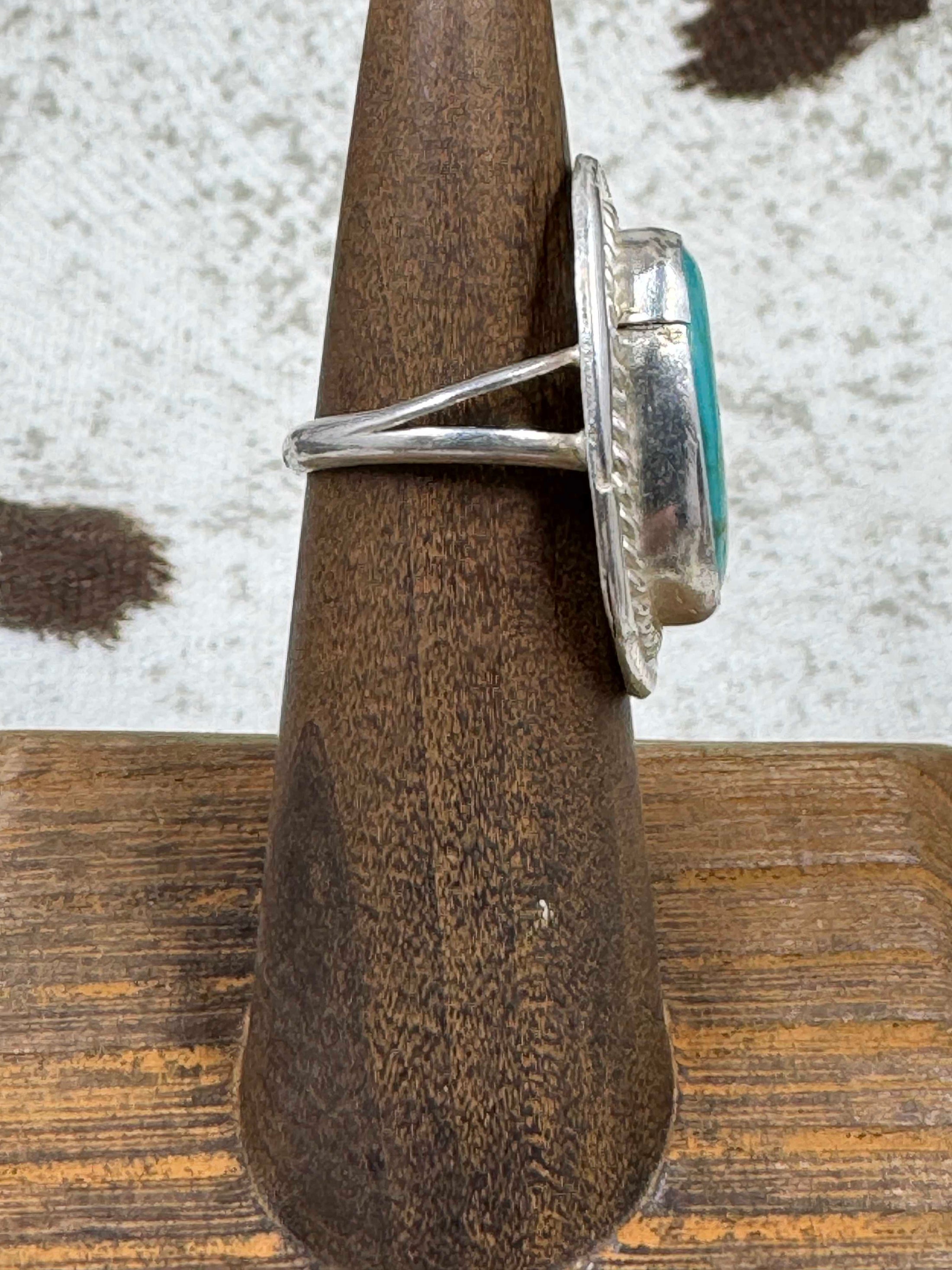 Side view Vintage Sterling Silver and Turquoise Ring on wood stand with cowhide background