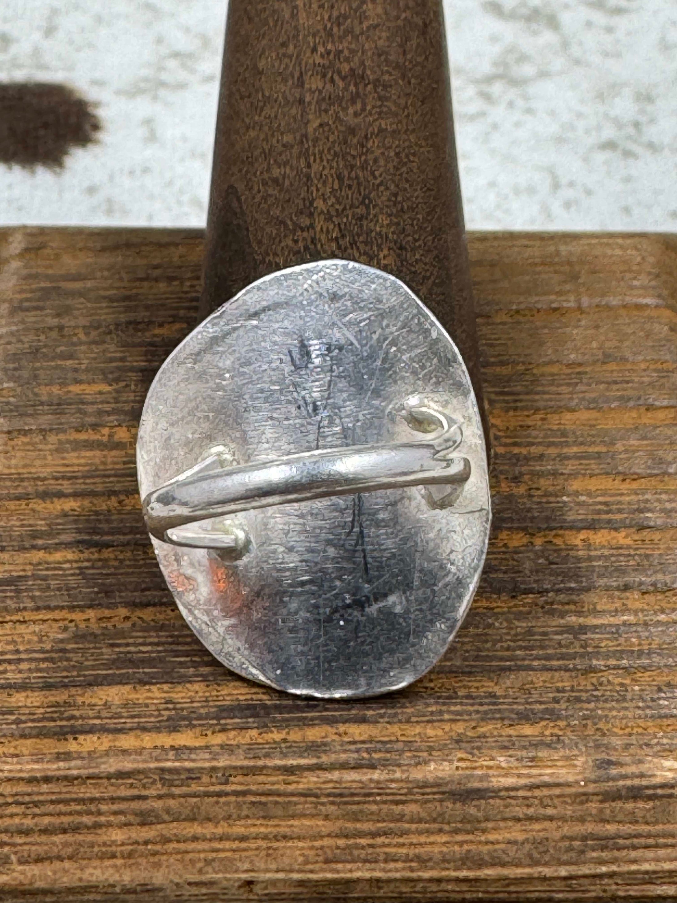 Back side of Vintage Sterling Silver and Turquoise Ring on wood stand with cowhide background