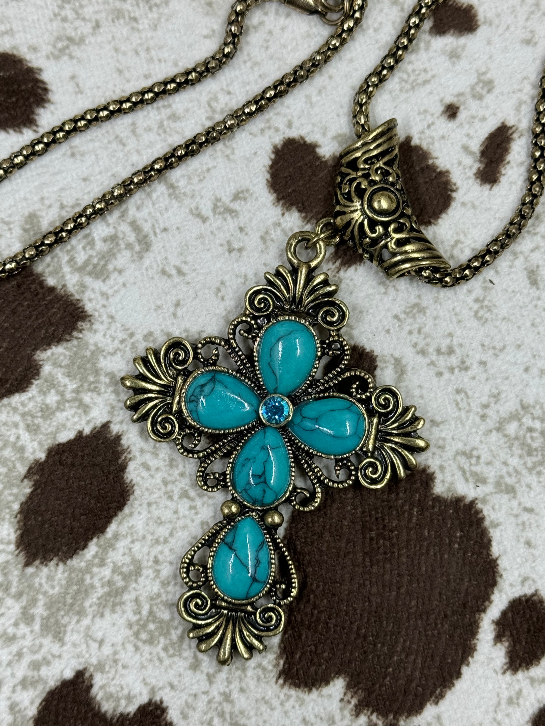 Faux Turquoise Cross on cowhide background