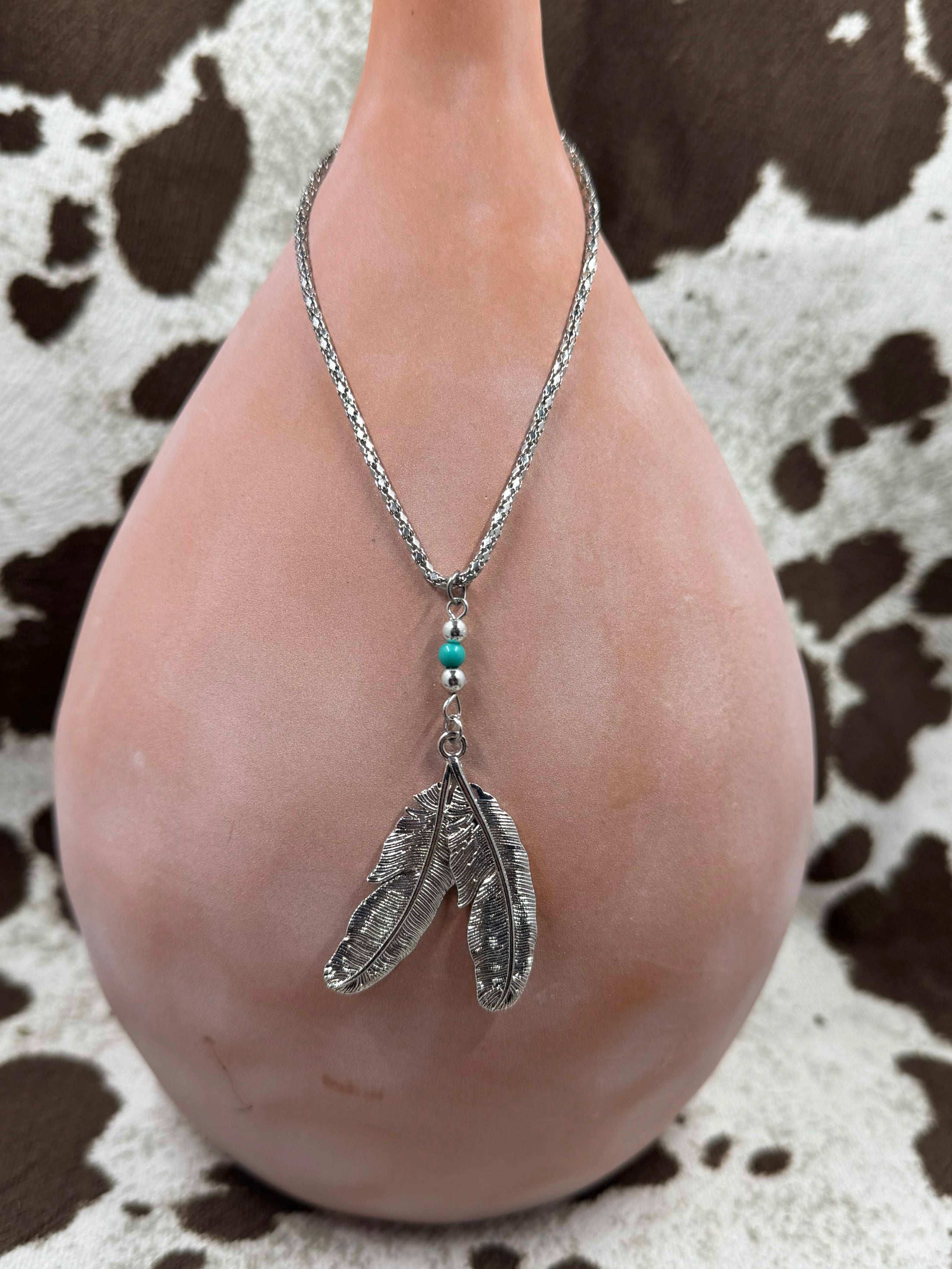 Silver feather necklace on brown vase