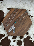 Load image into Gallery viewer, Silver feather necklace on brown block and cowhide print
