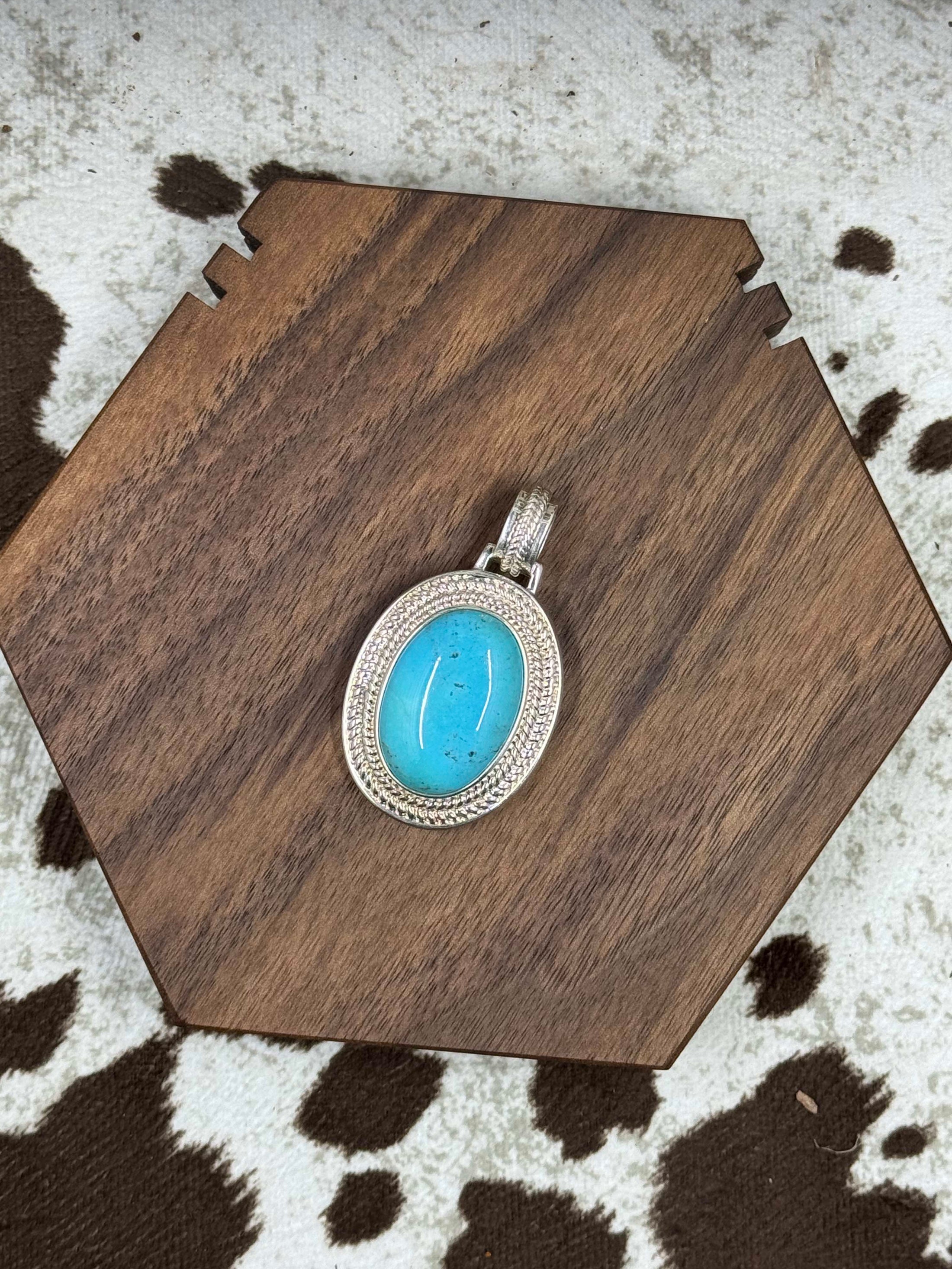 Front of pendant enhancer laying on brown block on cowhide background