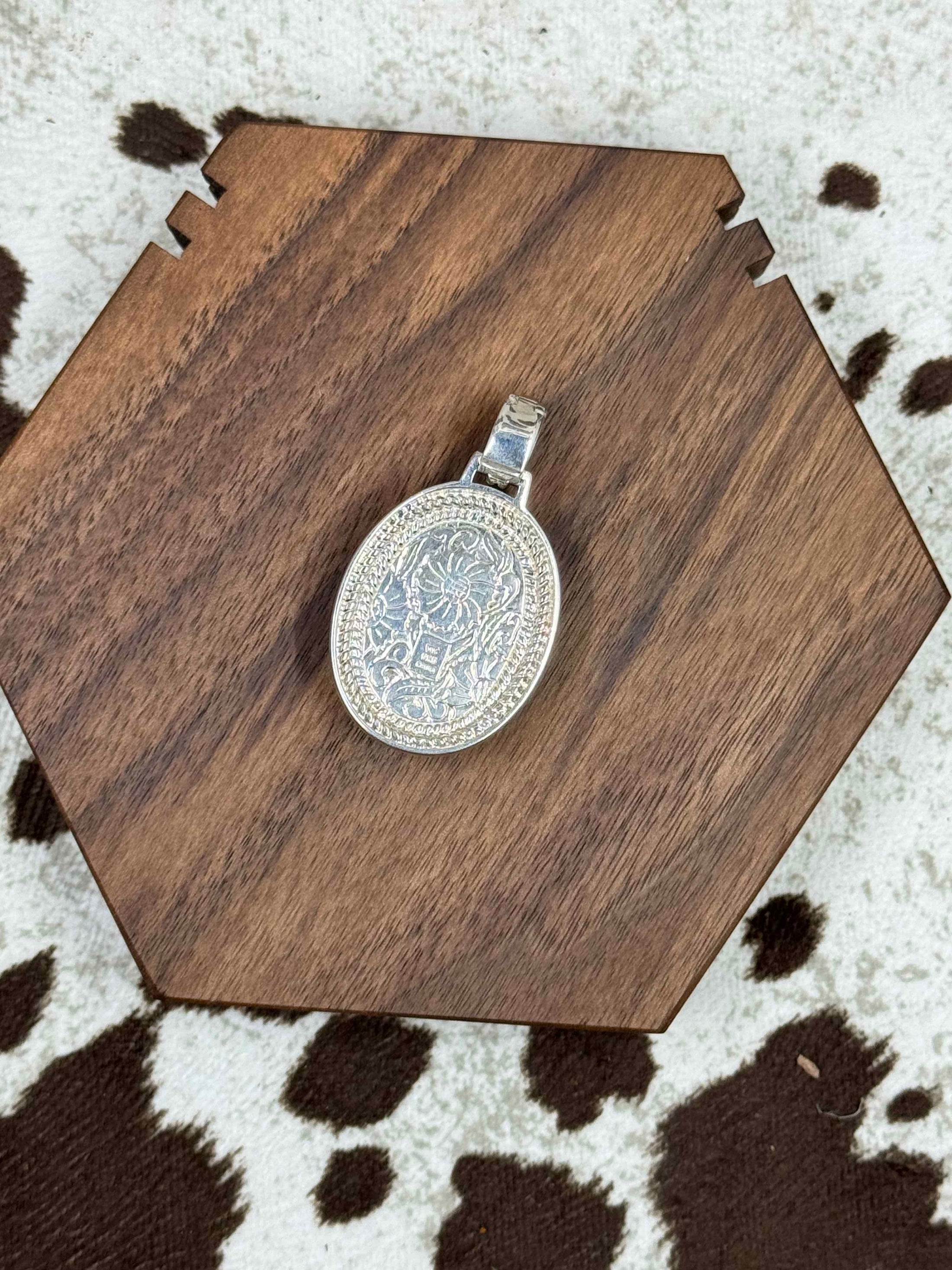 back of silver pendant enhancer on brown block on cowhide background