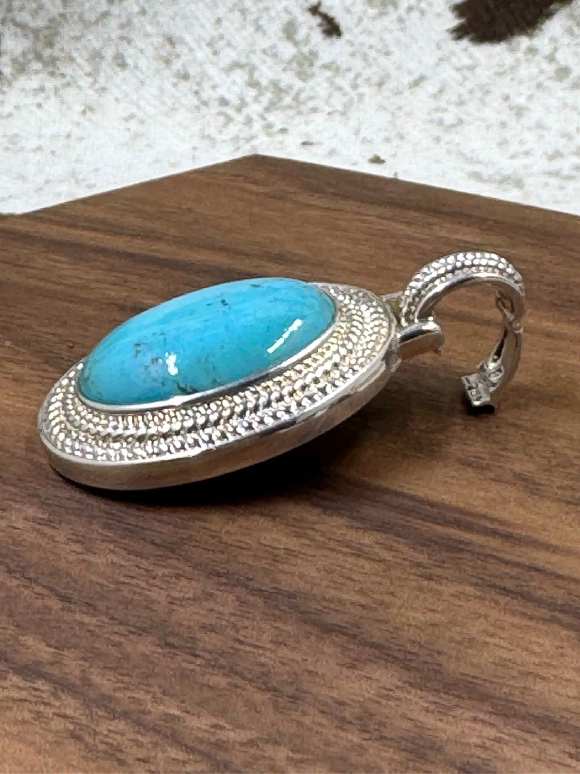 Turquoise Pendant Enhancer laying open on a brown block and cowhide background