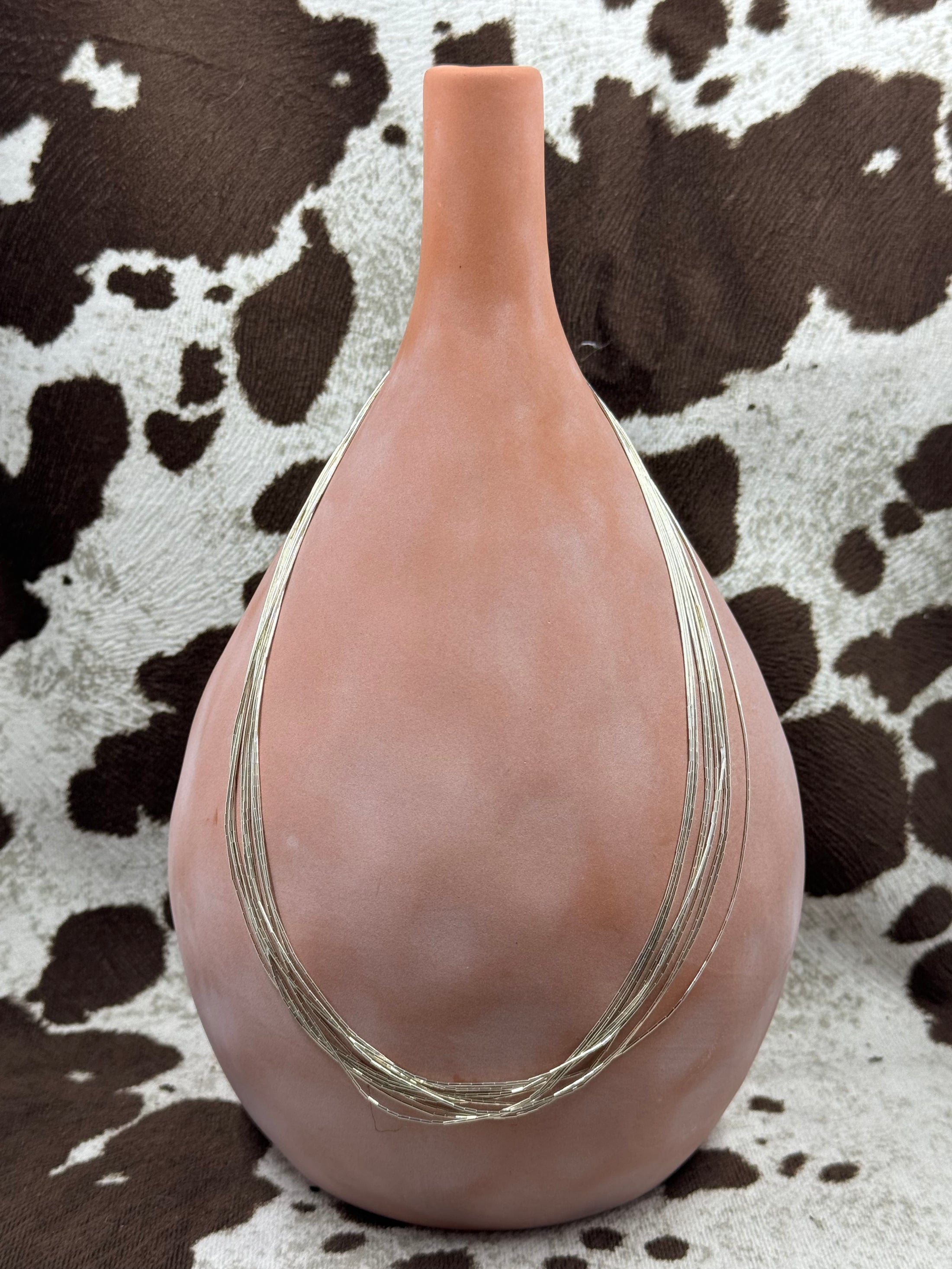 Southwest Style Polished Sterling Silver Liquid 10 strand Necklace around terra cotta bottle with cowhide background