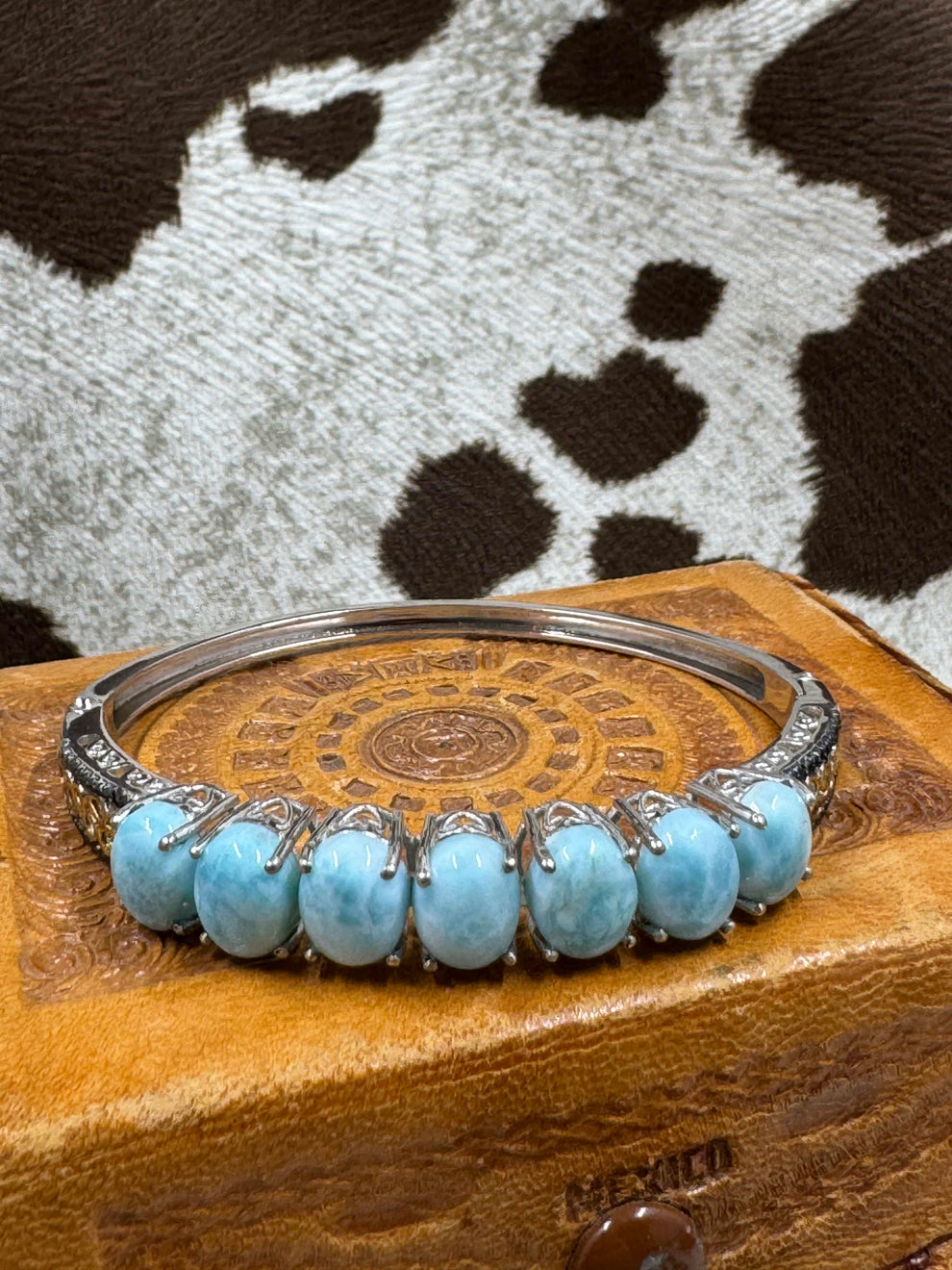 Silver Hinged Bangle Bracelet with Larimar Cabochons on leather jewelry box with cowhide background