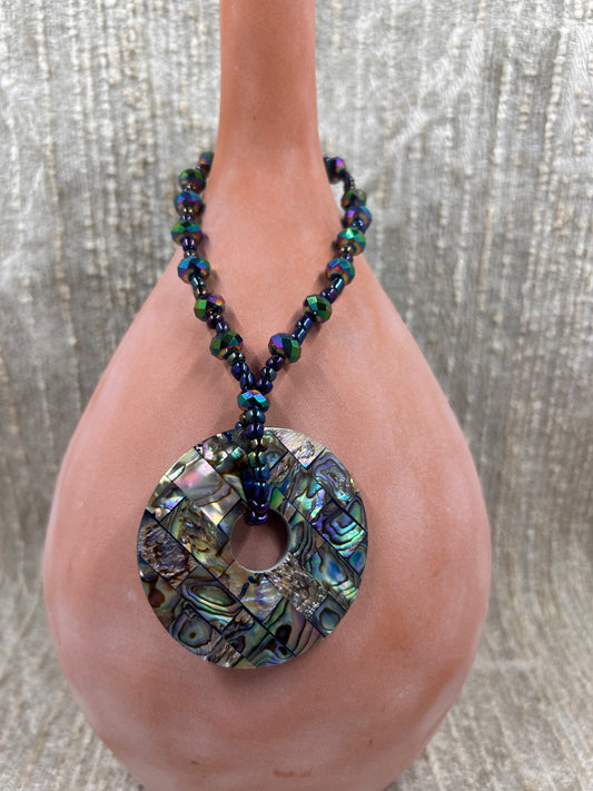 Beaded Colorful Necklace with Inlayed Multi Colored Squares Circle Pendant on brown vase with white background