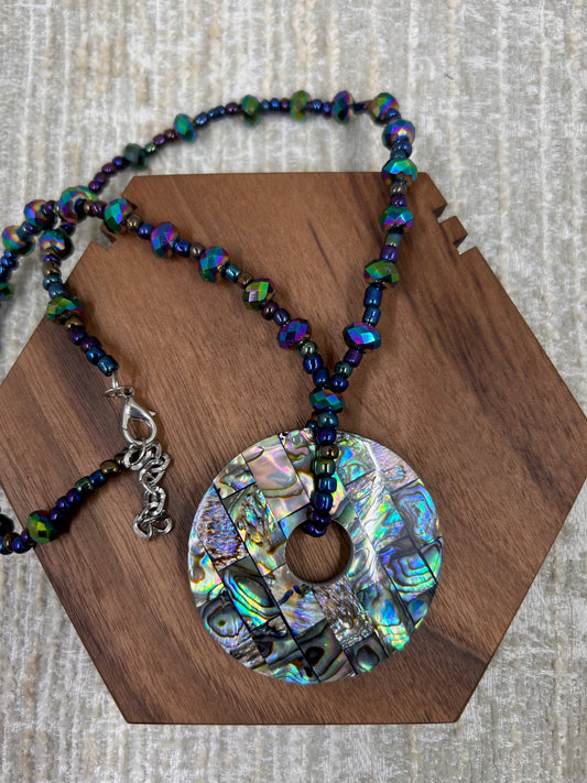 Beaded Colorful Necklace with Inlayed Multi Colored Squares Circle Pendant on brown wood block and white background