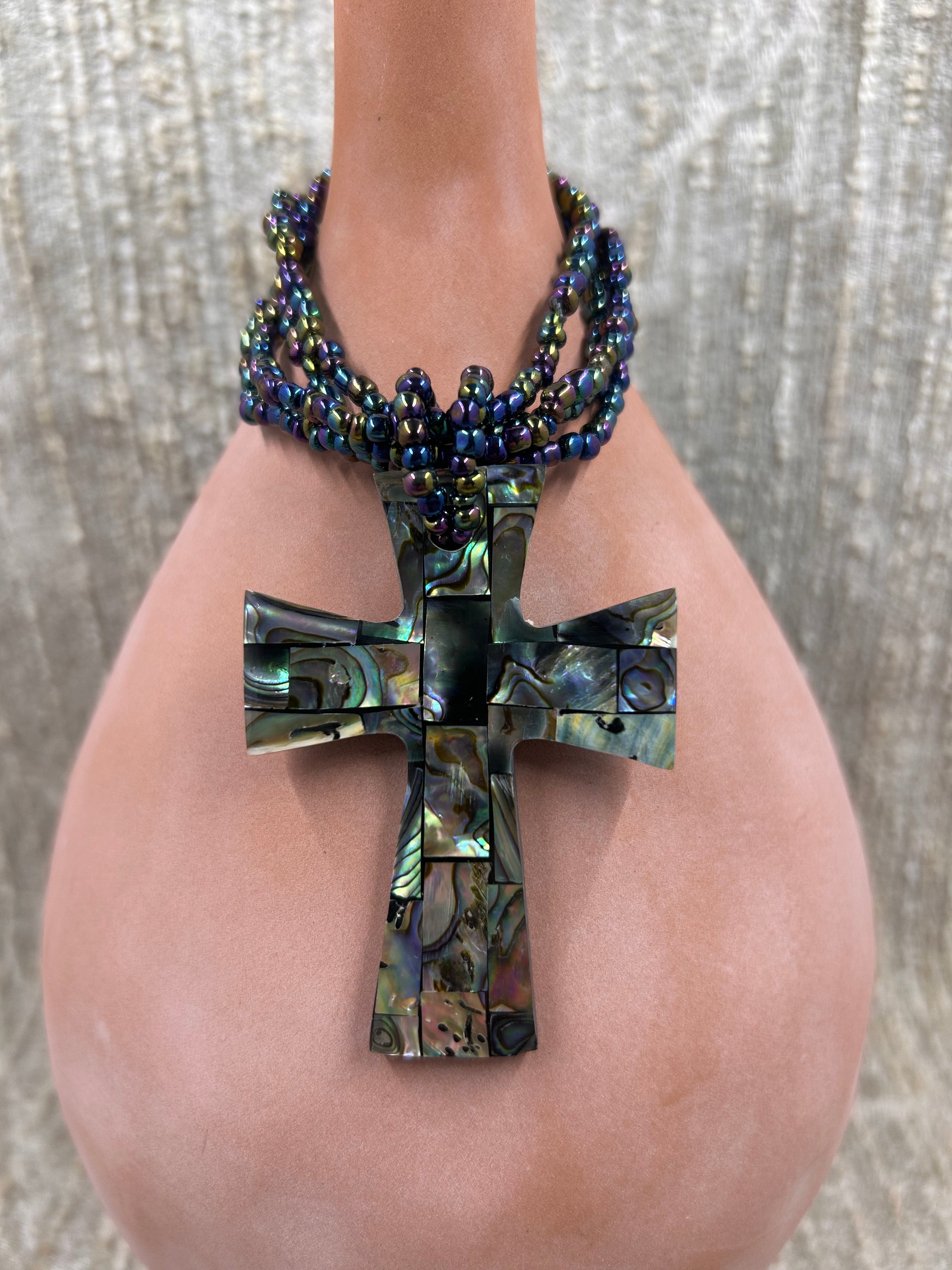 Colorful beaded necklace with inlayed cross on brown bottle 