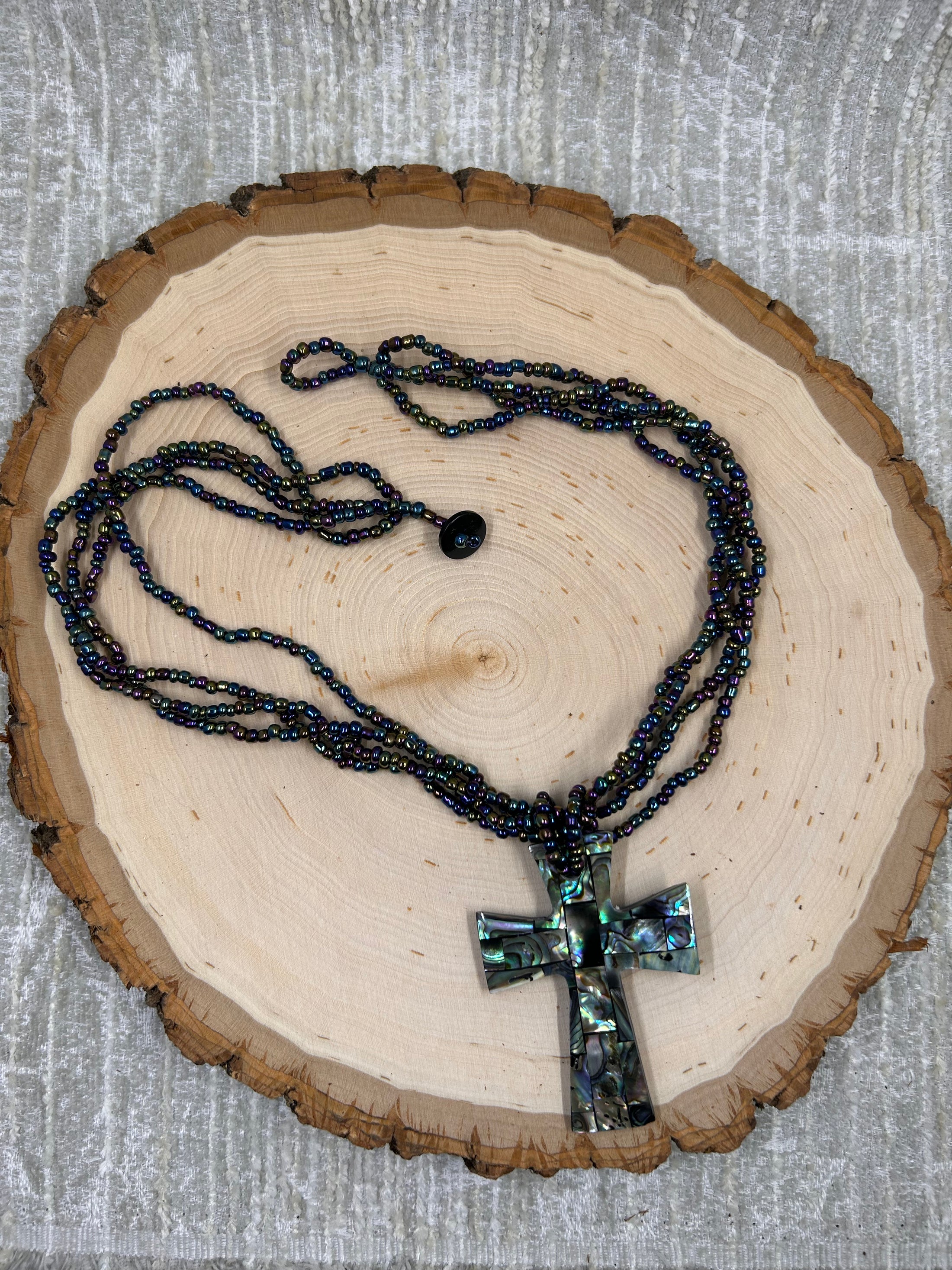 colorful beaded necklace with inlayed cross on wood block