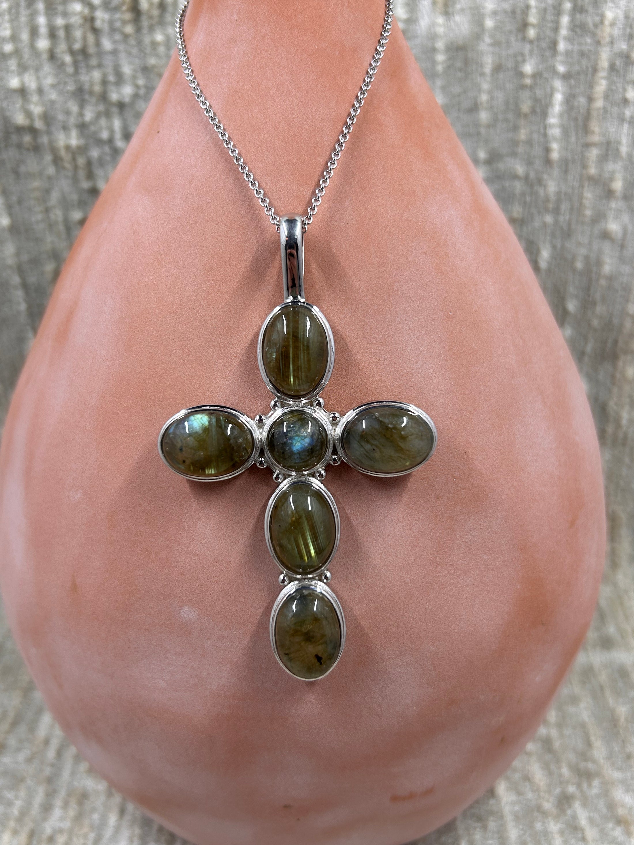 Labradorite Cross Pendant with Sterling Silver Chain on brown vase with white background