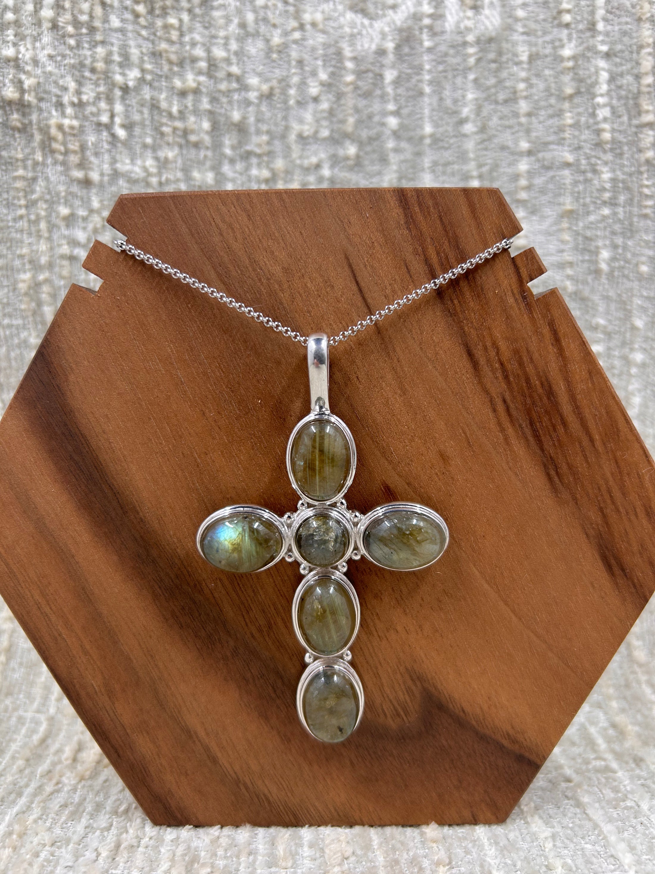 Labradorite Cross Pendant with Sterling Silver Chain on wood block with white background