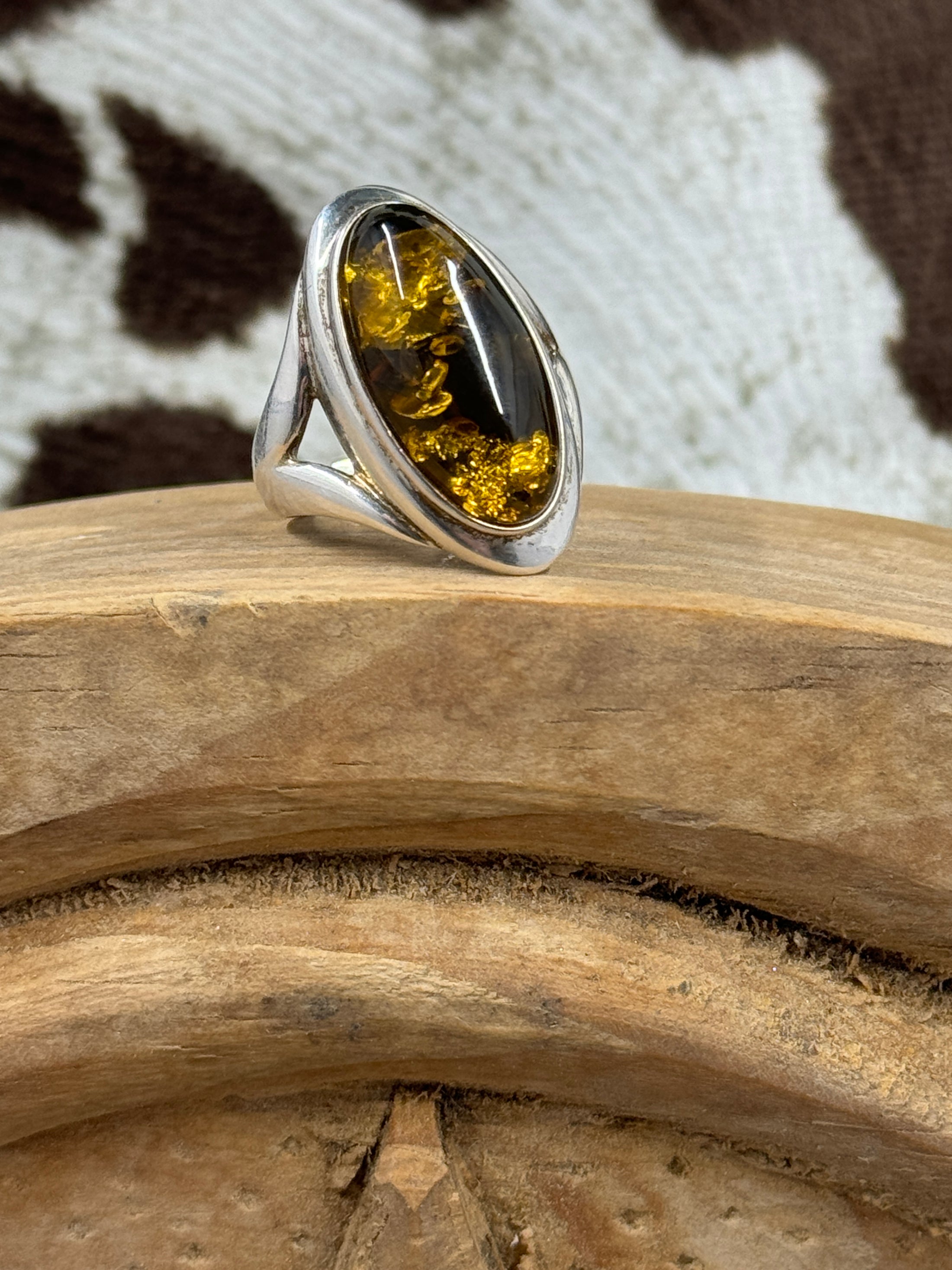 Sterling silver amber ring on wood block with cowhide background