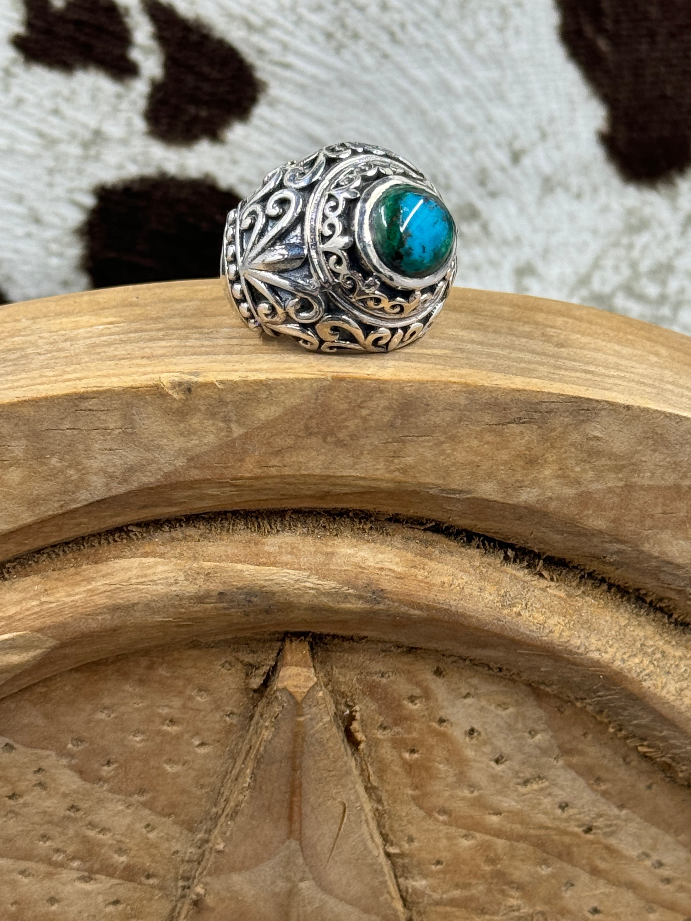 Chrysocolla Stone Cabochon ring sitting on a wood block with cowhide background