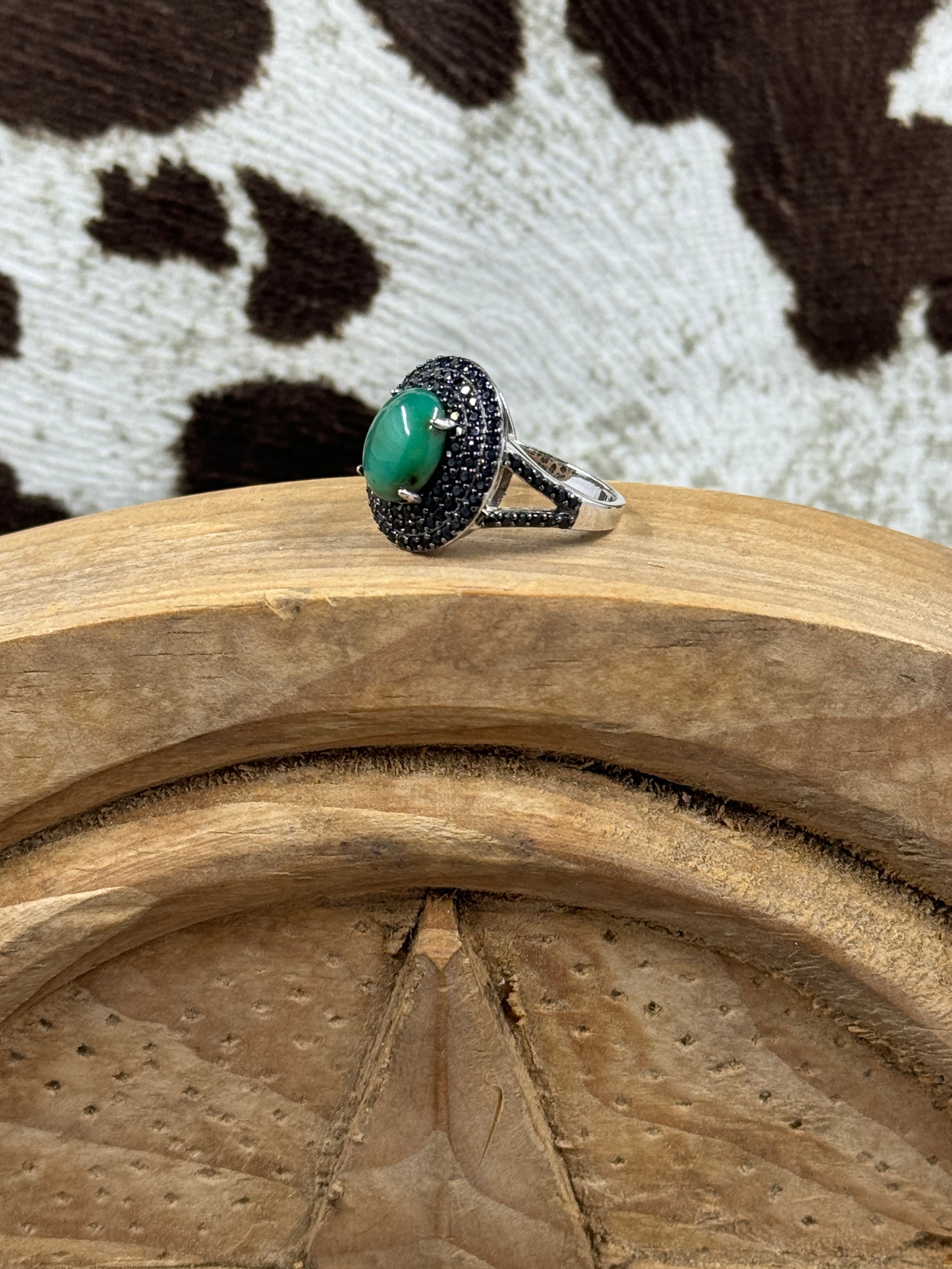 Green Onyx and Spinel Ring sitting on wood block and cowhide background