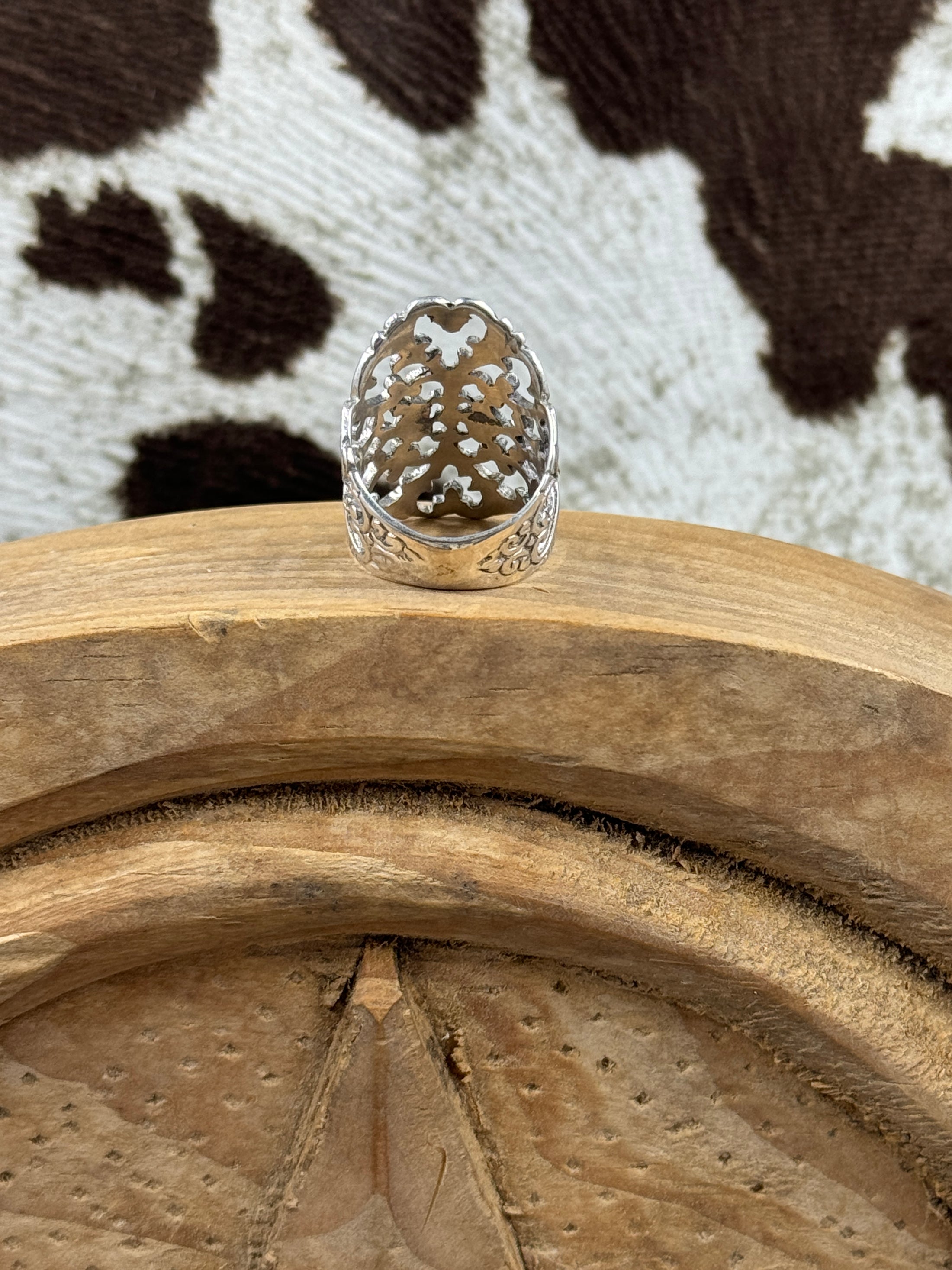 Underside of sterling silver ring on wood block with cowhide background