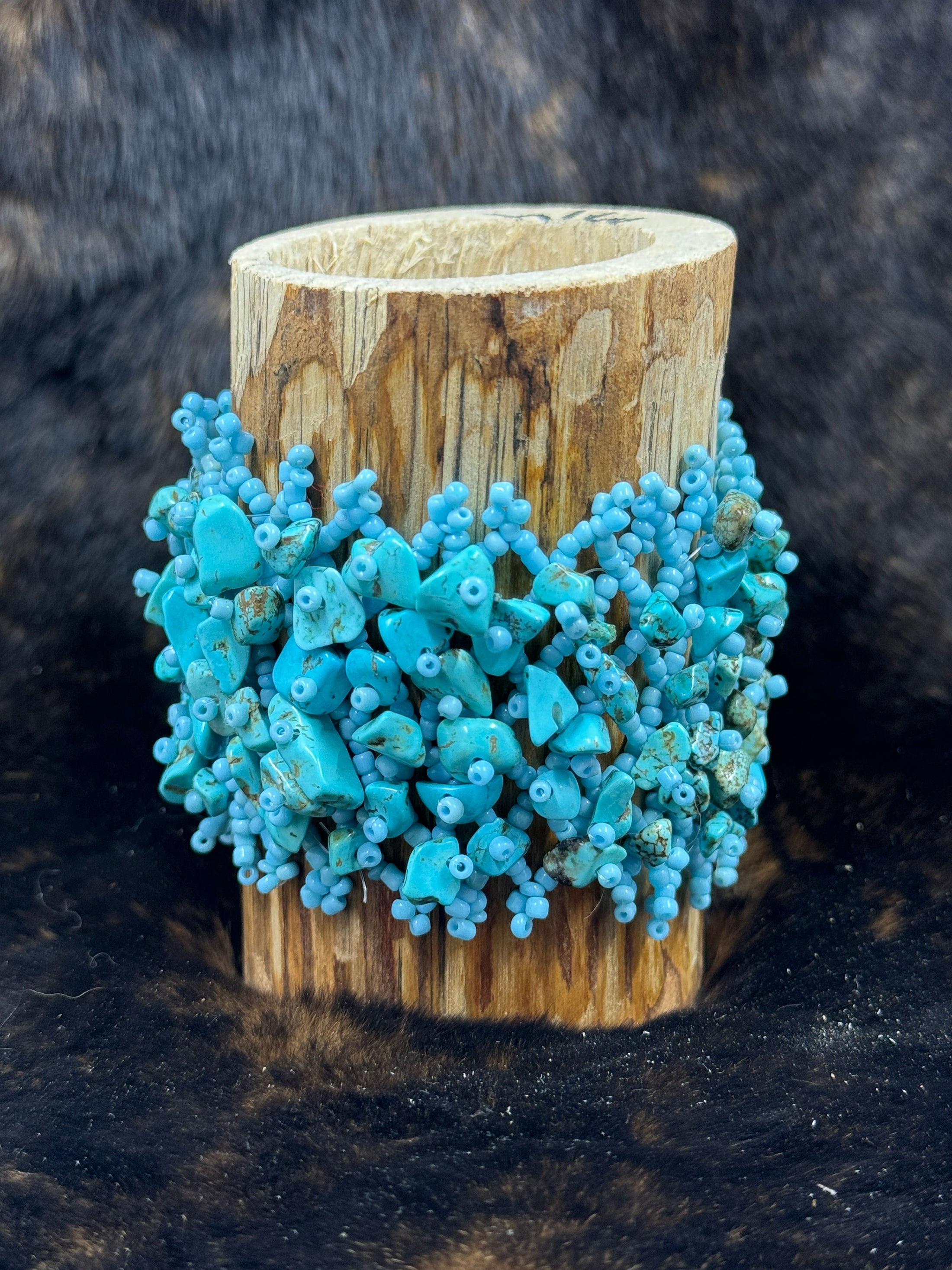 Handcrafted Turqoise Beaded Bracelet around a wood cup with dark fur background