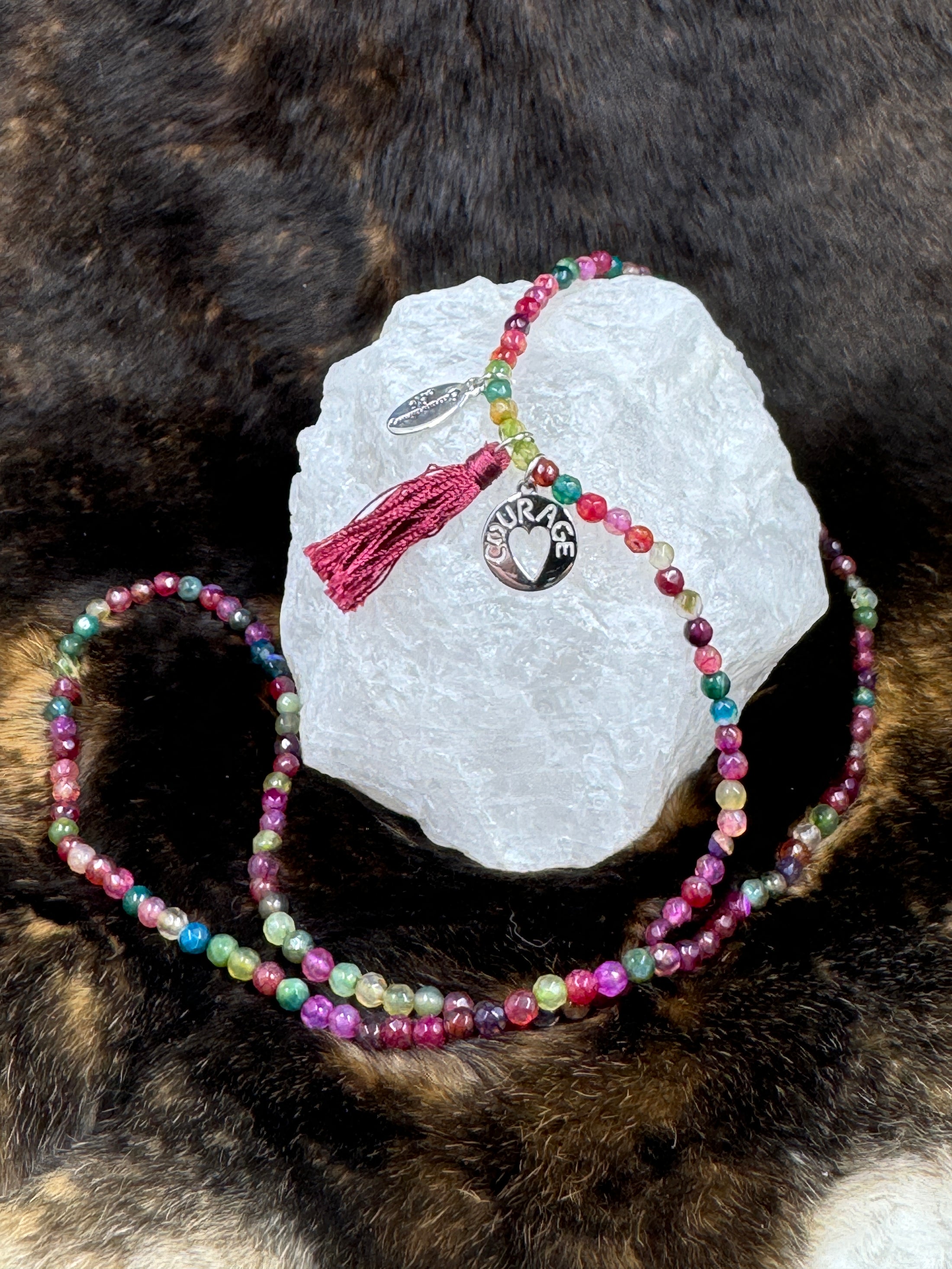 Multi Color beaded necklace with courage charm on white rock with dark fur background