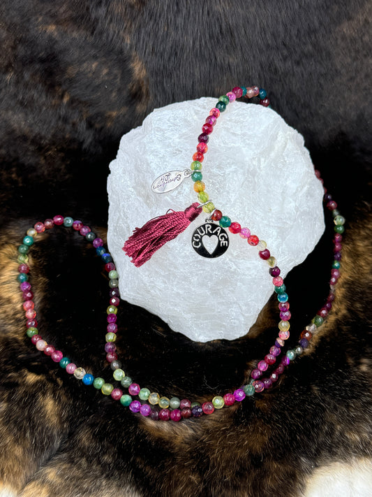 Multi Color beaded necklace with courage charm on white rock with dark fur background