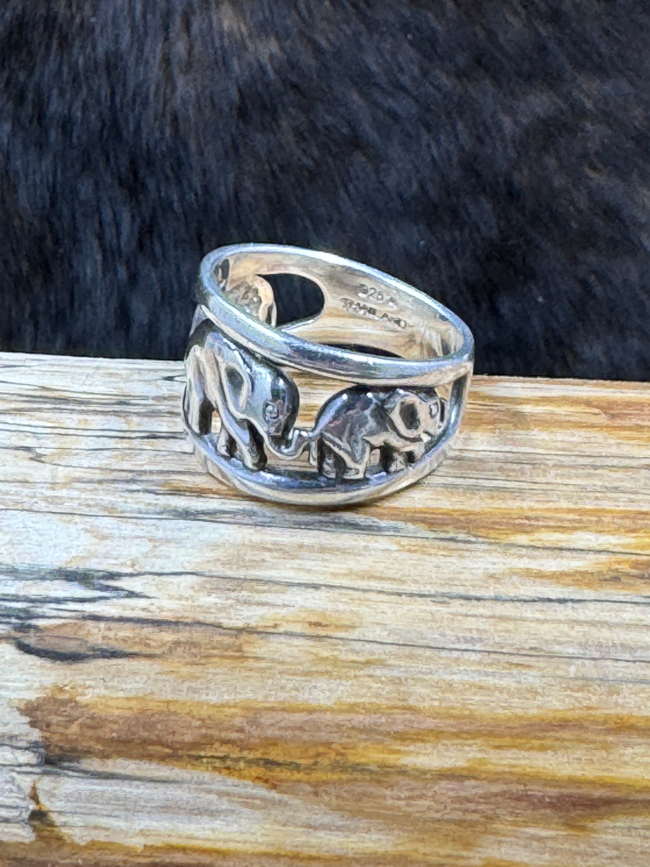 Side view Vintage Sterling Silver Elephant with Babies Ring on wood block with dark fur background also shows 925 mark