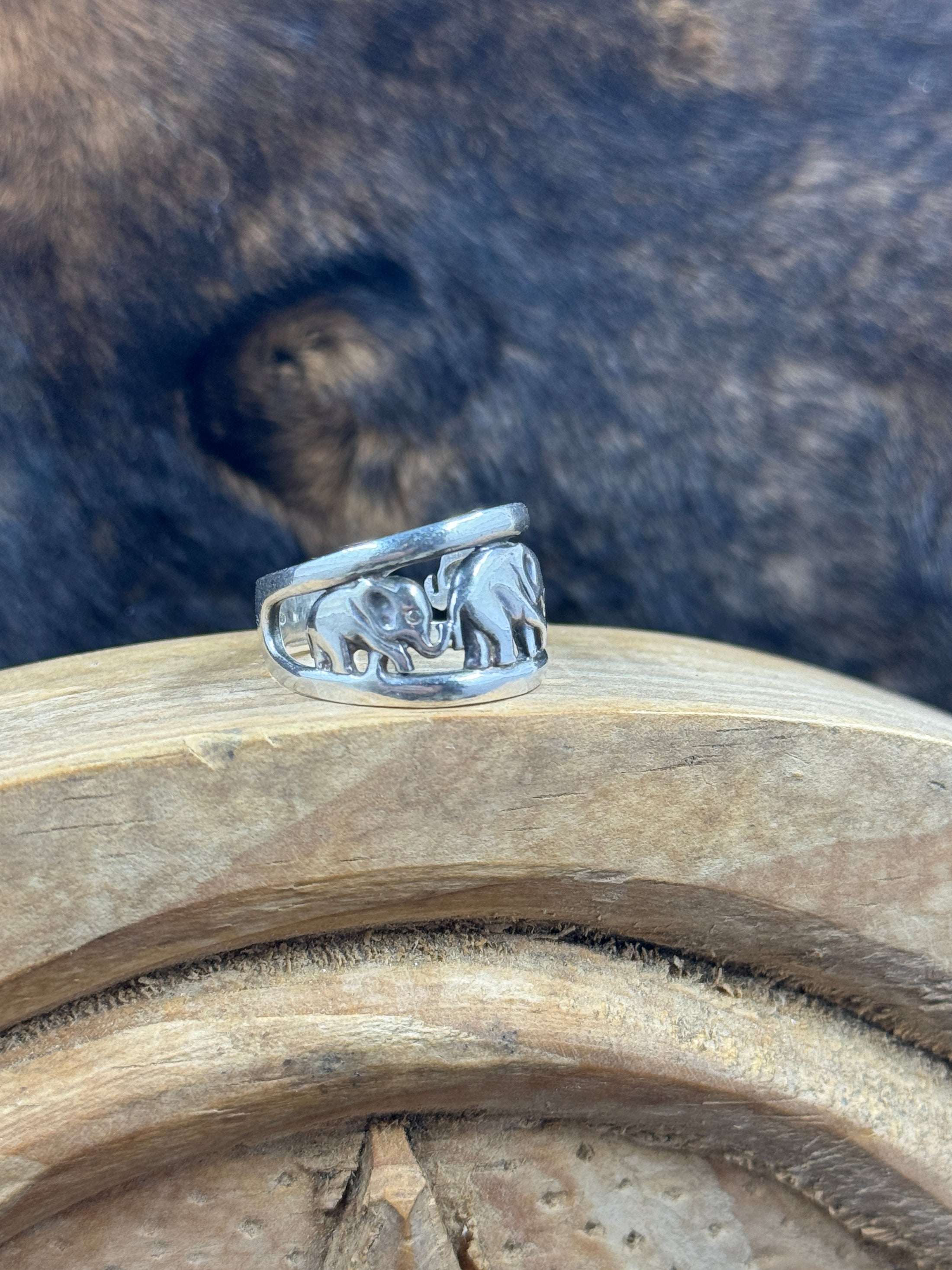 Side view Vintage Sterling Silver Elephant with Babies Ring on wood block with dark fur background