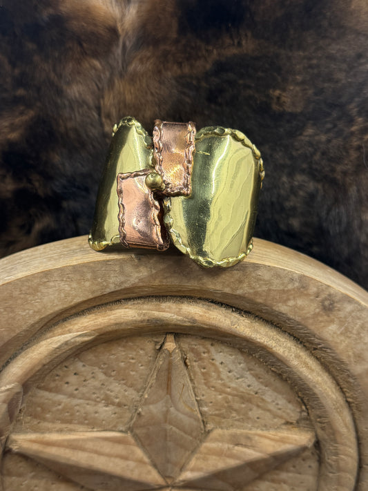 aUnique Brass and Copper Bracelet on wood block with dark fur background