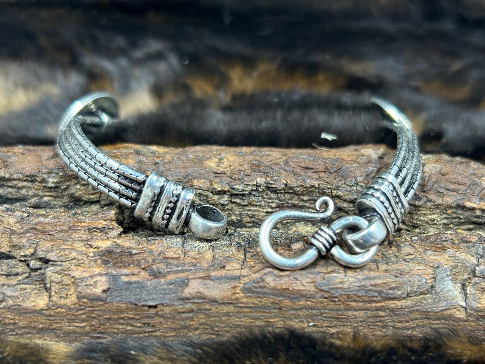 Back of coin bracelet showing clasp on wood block with fuzzy fur background