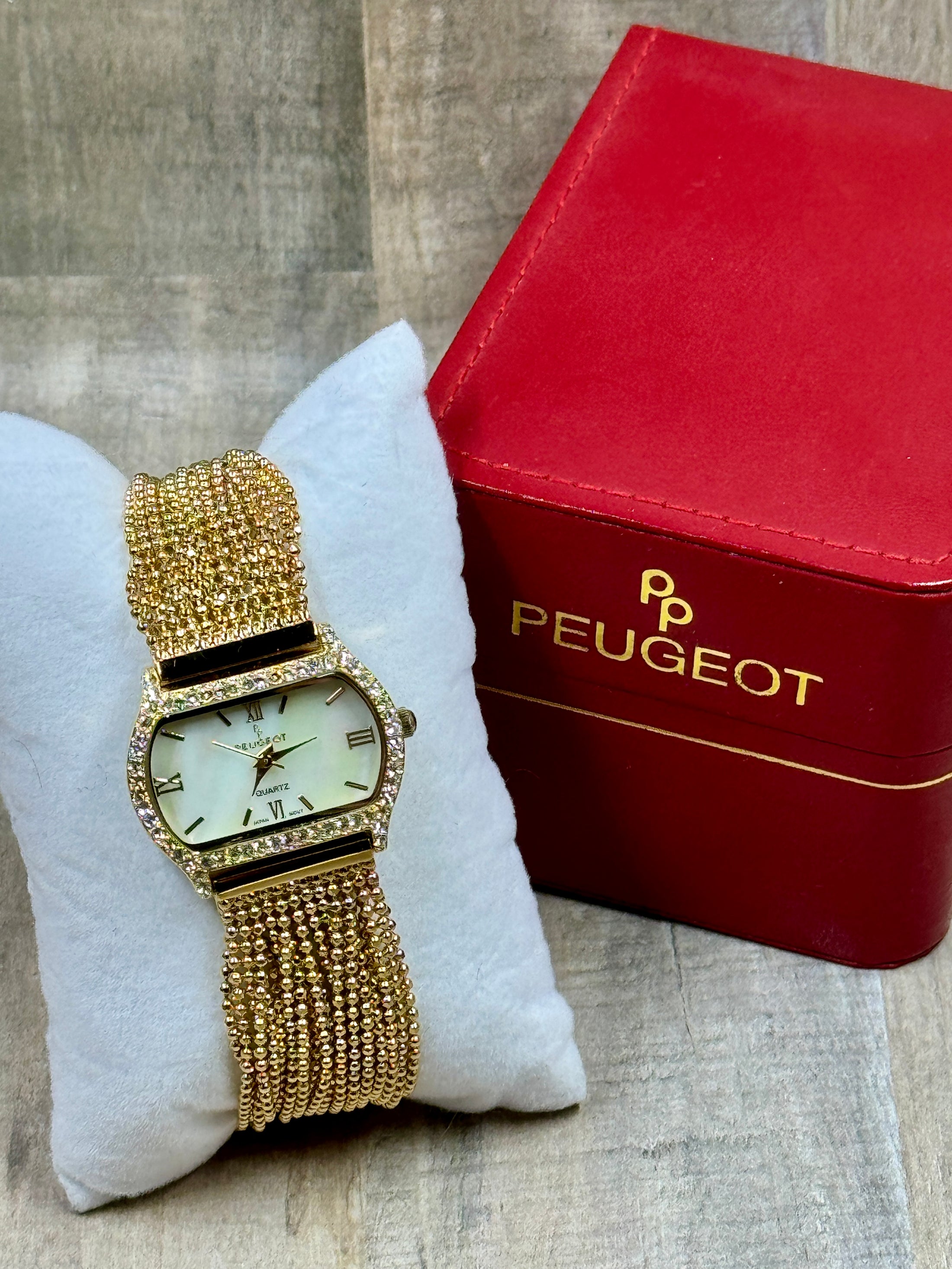 Peugeut Gold and Crystal Ladies Watch on wood back ground with red box