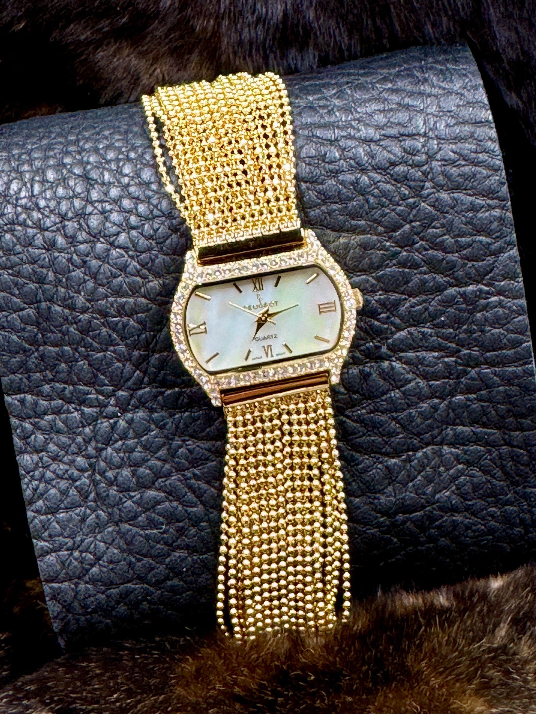 Peugeut Gold and Crystal Ladies Watch laying on leather background