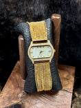 Load image into Gallery viewer, Peugeut Gold and Crystal Ladies Watch on black leather and wood stand with fur background
