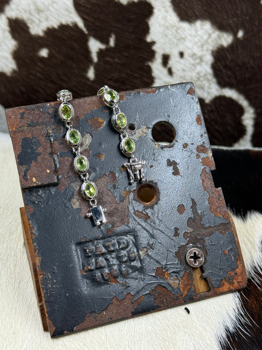 Silver Stainless Steel and Peridot Gem Bracelet on metal stand with cowhide background