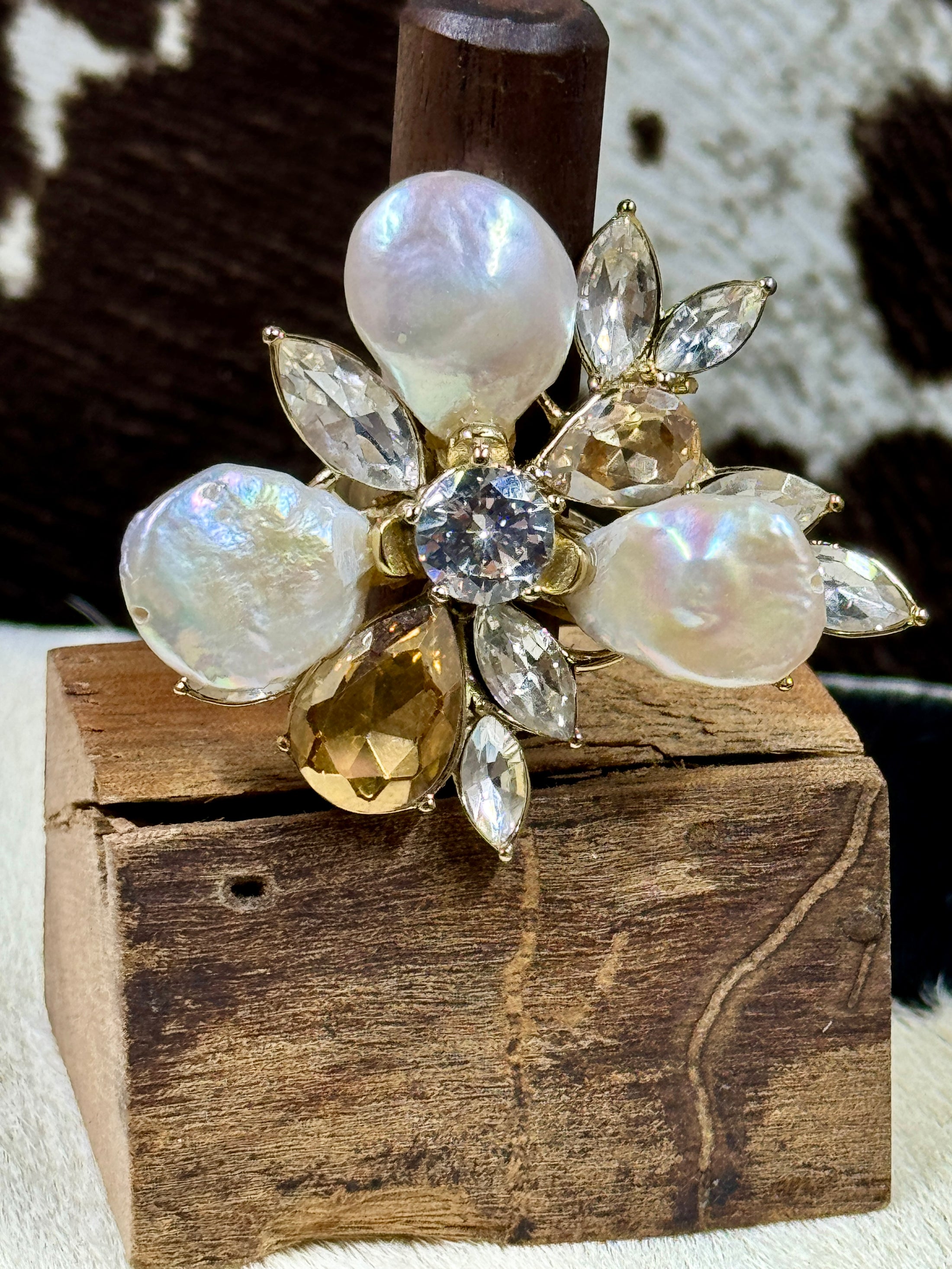 Faux Pearl and Crystal Flower Ring on wood block with cowhide background