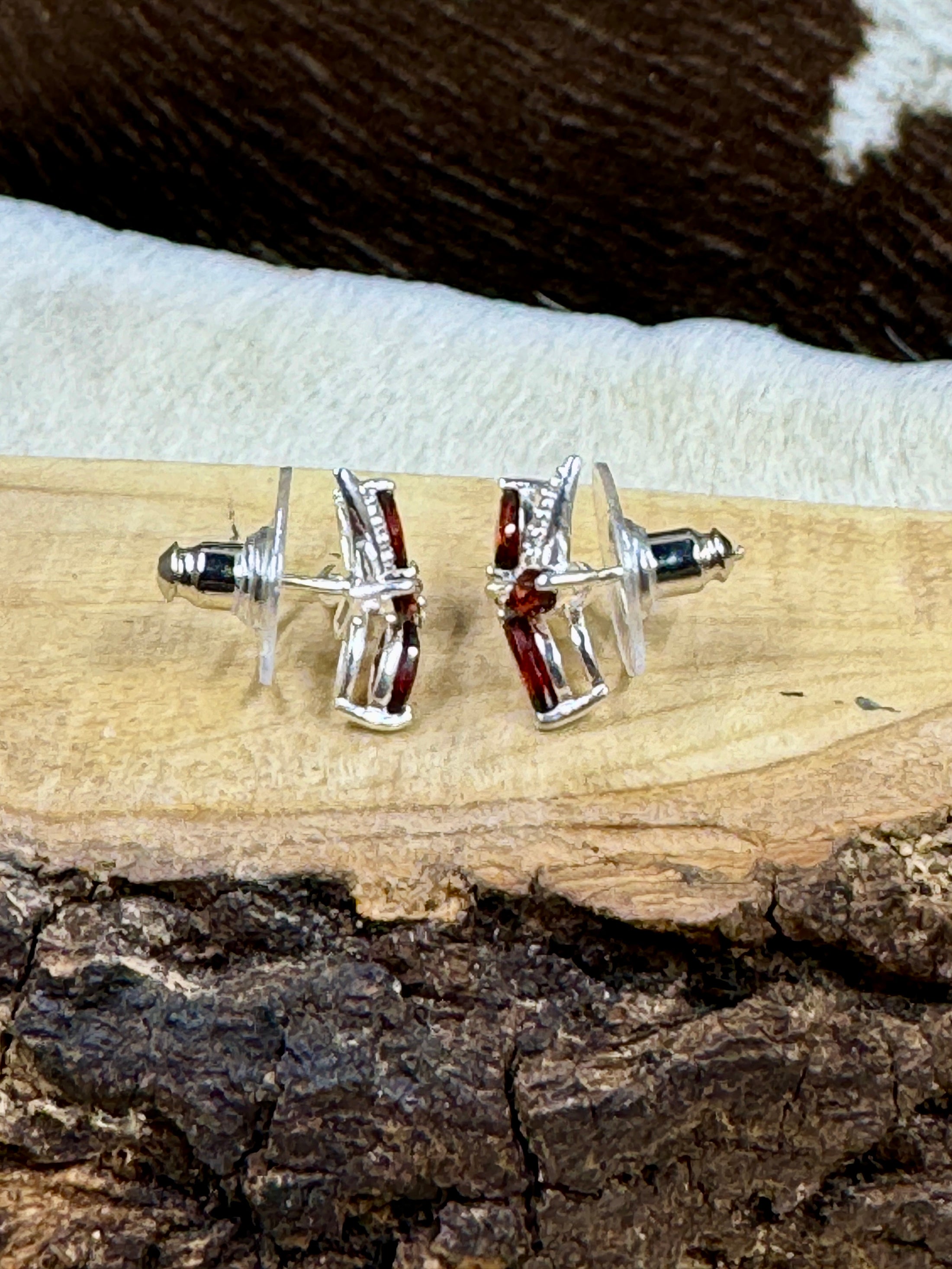 Side view Garnet Butterfly and Sterling Earrings on wood block with cowhide background